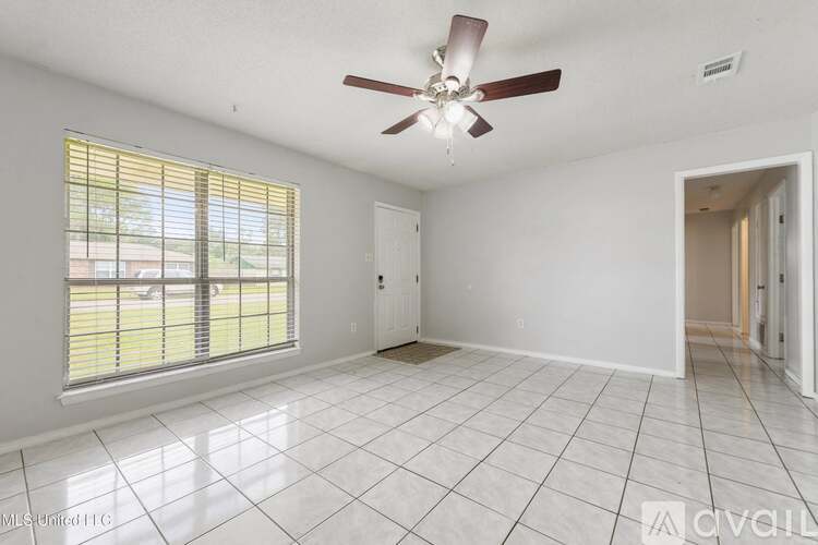A spacious room with a ceiling fan and a large window with blinds.
