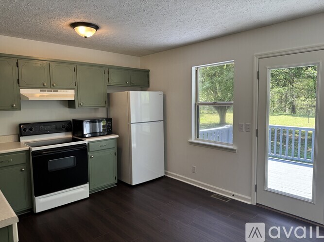 A kitchen with green cabinets and white appliances.