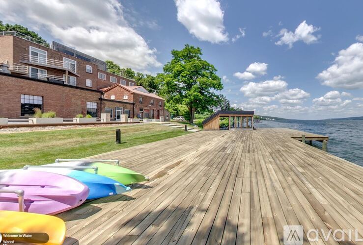A wooden dock with colorful kayaks and a building in the background.