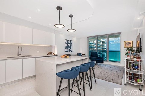 A modern kitchen with white cabinets and a bar area.
