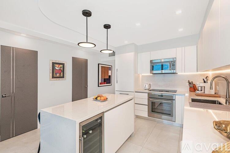 A modern kitchen with a white island and stainless steel appliances.