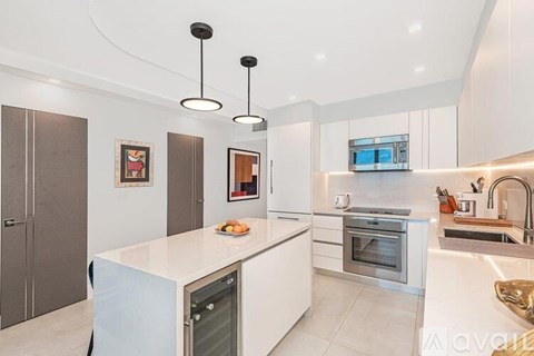 A modern kitchen with a white island and stainless steel appliances.