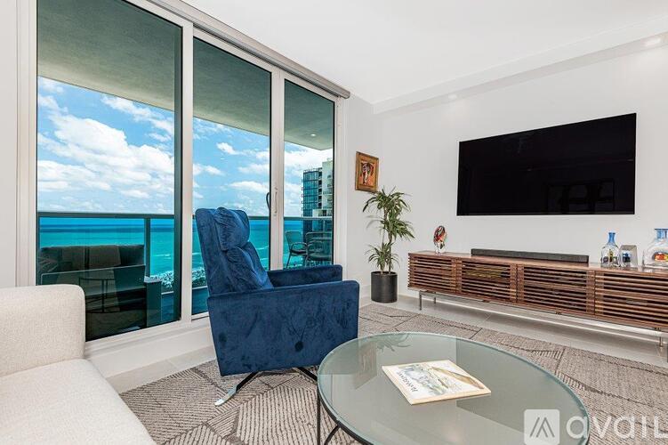 A living room with a blue chair and a glass table.