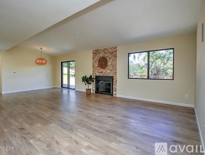 A spacious living room with a fireplace and a large window.