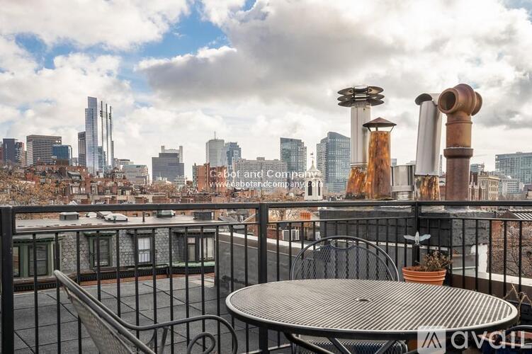 A balcony with a table and chairs overlooking a city skyline.