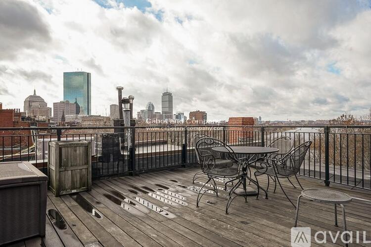 A balcony with a table and chairs overlooking a city skyline.