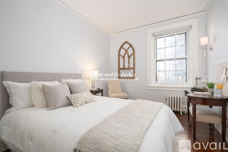 A bedroom with a large bed and a window with a white frame.
