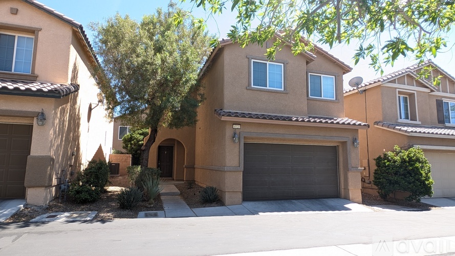 A house with a tan exterior and a grey garage door.