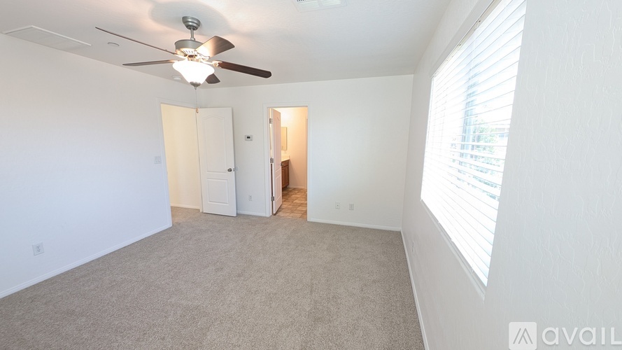 A room with a ceiling fan and carpeted floor.