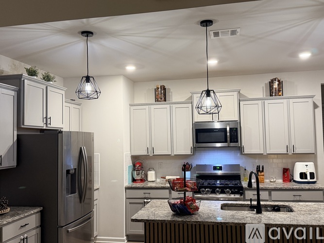 A kitchen with a refrigerator, microwave, and oven.