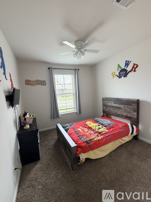 A bedroom with a bed, a ceiling fan, and a window with a view of the outside.