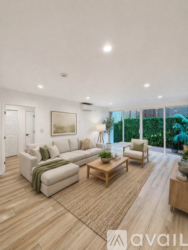 A living room with a white couch, a wooden coffee table, and a painting on the wall.