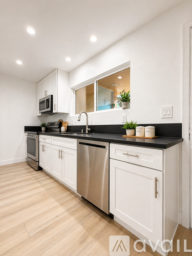 A modern kitchen with white cabinets and stainless steel appliances.