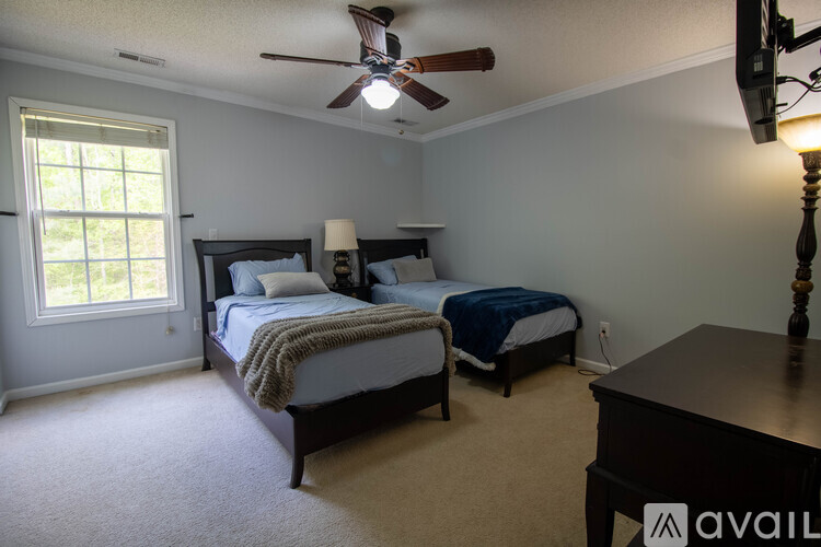 A bedroom with two beds and a ceiling fan.