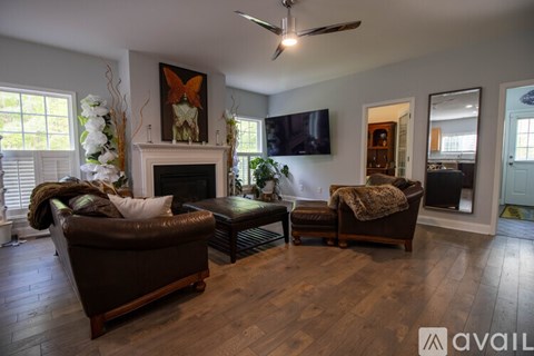 A living room with a brown couch, a fireplace, and a painting on the wall.