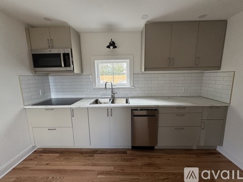 A kitchen with white cabinets and a window.