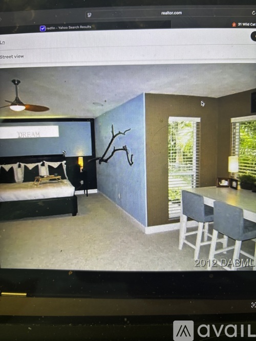 A bedroom with a bed, a desk, and a chair is displayed on a website.