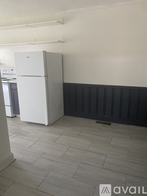 A white refrigerator in a kitchen with a black strip on the wall.