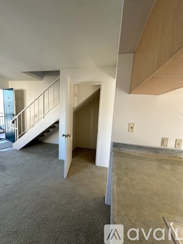 A room with a carpeted floor and a staircase with a railing.