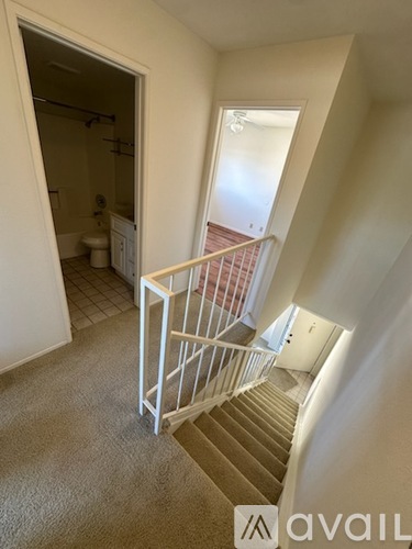 A carpeted staircase with a metal railing leads to a bathroom.