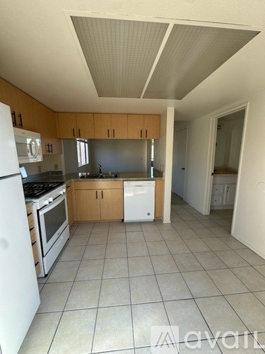 A kitchen with white appliances and wooden cabinets.