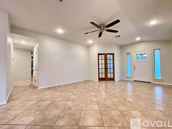 A spacious room with a ceiling fan and tiled flooring.