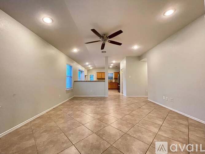 A spacious room with a ceiling fan and tiled flooring.
