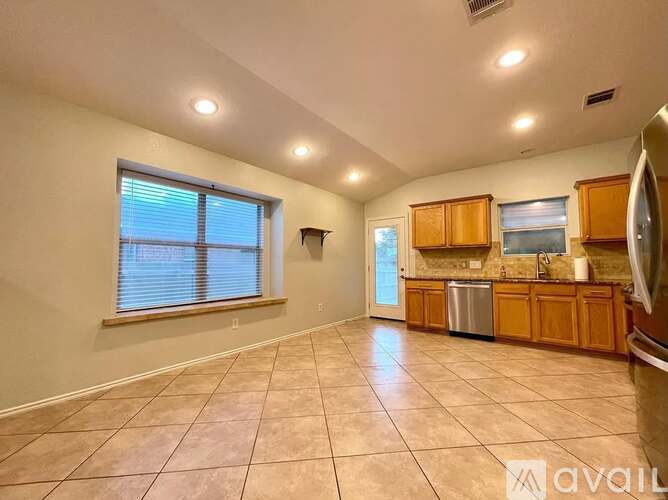 A spacious kitchen with wooden cabinets and a tiled floor.