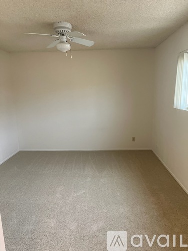A room with a ceiling fan and carpeted floor.