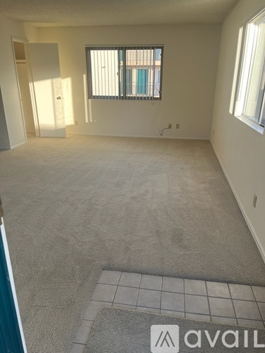 A room with a carpeted floor and a window with bars on it.