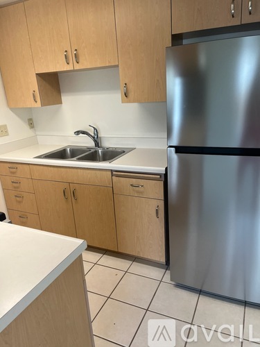 A kitchen with a stainless steel refrigerator and wooden cabinets.