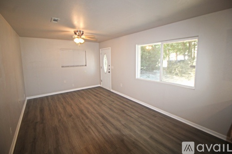 A room with wooden floors and a window with a view of trees.