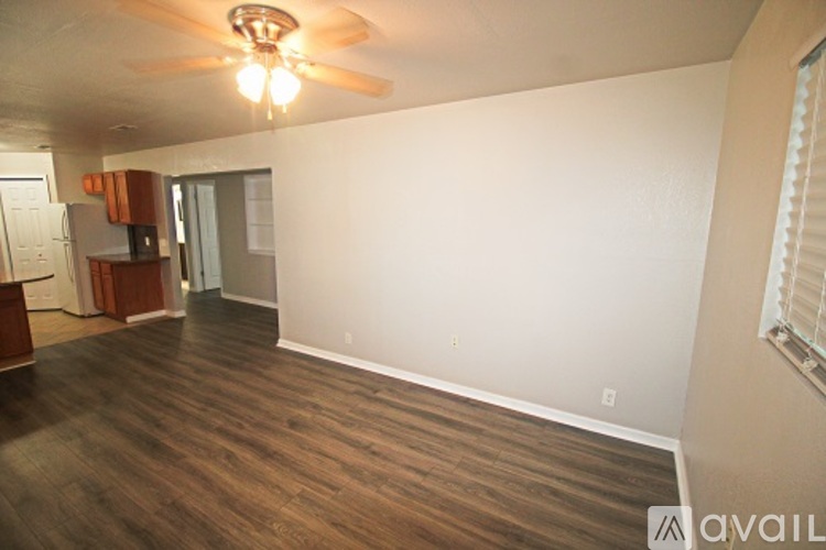 A room with a ceiling fan and wooden flooring.