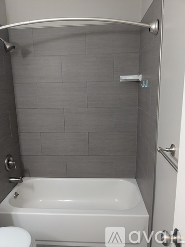 A white bathtub in a bathroom with grey tiles.