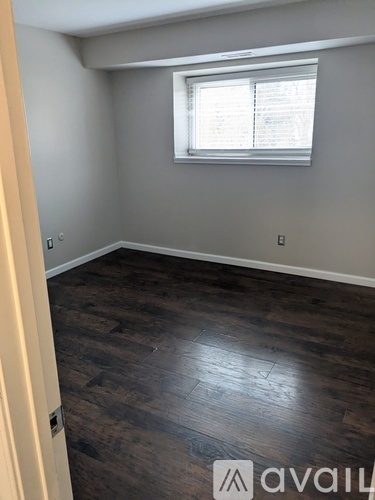 A room with wooden flooring and a window with blinds.