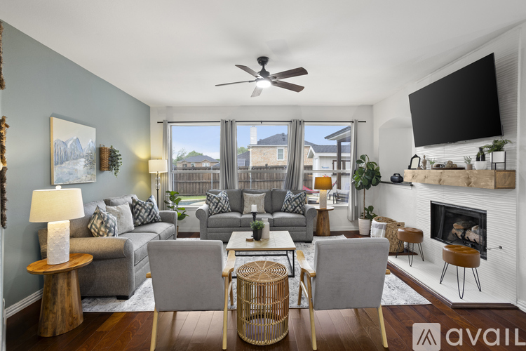 A living room with a grey couch, a fireplace, and a television mounted on the wall.