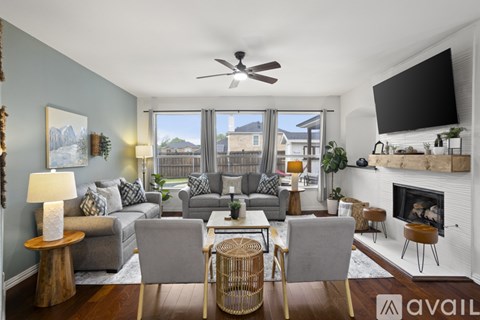 A living room with a grey couch, a fireplace, and a television mounted on the wall.