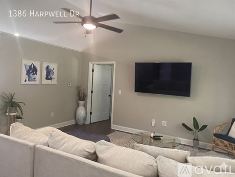 A living room with a white couch and a flat screen TV mounted on the wall.