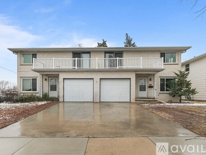 A two-story house with a balcony and two garages.