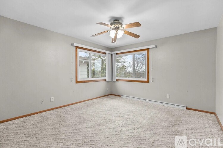 A room with a ceiling fan and a window with a view of trees.