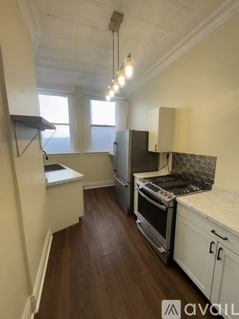 A kitchen with wooden floors and white cabinets.