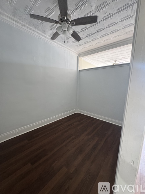 A room with a ceiling fan and wooden flooring.
