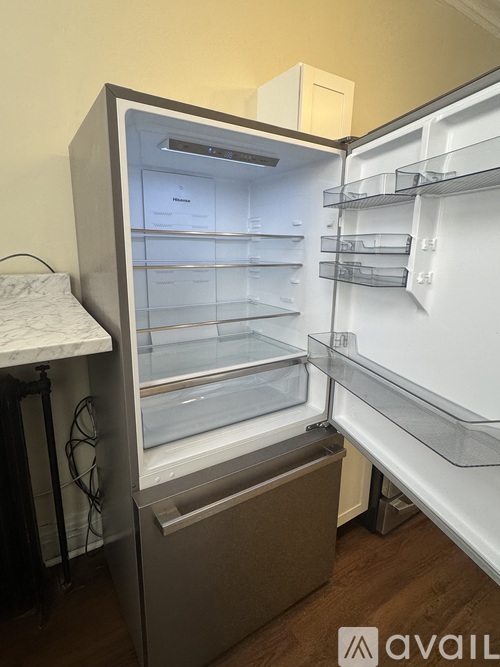A white refrigerator with its door open and empty shelves.