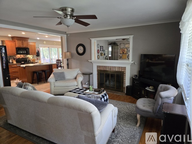 A living room with a grey couch, a fireplace, and a ceiling fan.