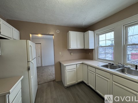 A kitchen with white cabinets and a refrigerator.