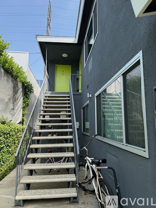 A bicycle is parked next to a set of stairs leading to a building with a yellow door.