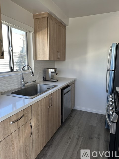 A kitchen with wooden cabinets and a black refrigerator.