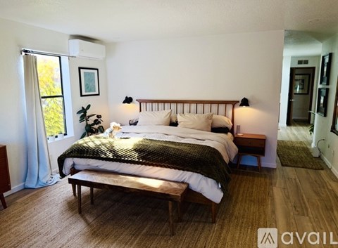 A bedroom with a large bed and a window with curtains.