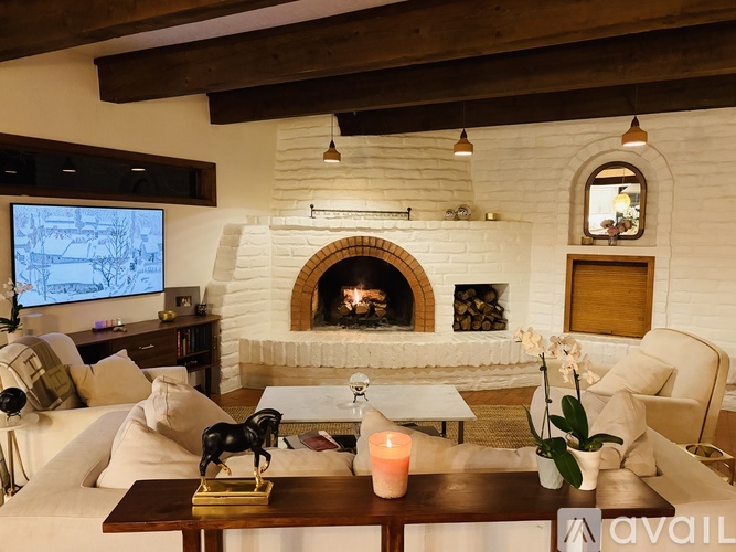 A living room with a fireplace and a TV on the wall.