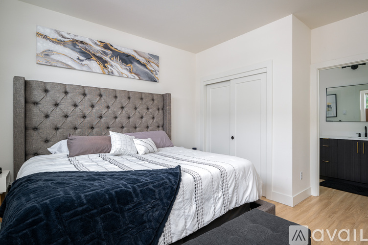 A bedroom with a large bed and a painting on the wall.